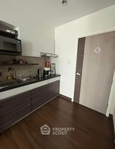 Modern kitchen with sleek cabinetry and appliances in a cozy apartment setting.