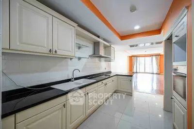 Spacious kitchen with sleek cabinetry and open layout leading to bright living area.