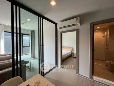 Modern apartment interior with glass partition, cozy living area, and bedroom view.