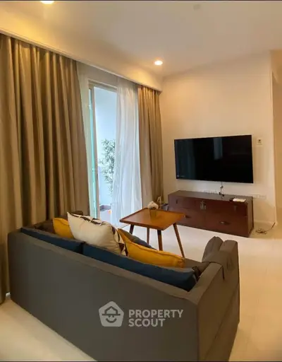 Modern living room with cozy sofa, wall-mounted TV, and elegant curtains in a stylish apartment.