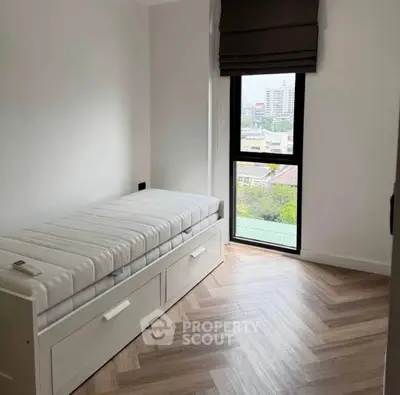 Minimalist bedroom with single bed and city view window, perfect for urban living.