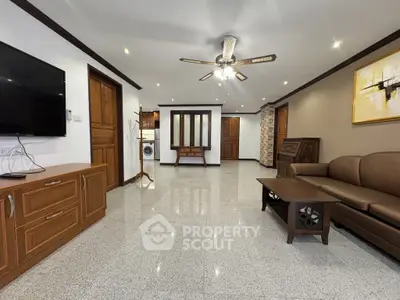 Spacious living room with modern decor and ceiling fan, featuring a wall-mounted TV and elegant furniture.