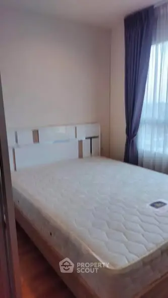 Cozy bedroom with natural light and modern decor, featuring a comfortable mattress and elegant curtains.