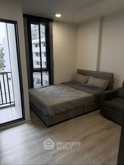Modern bedroom with balcony access and stylish decor in urban apartment.