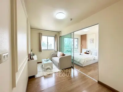 Modern apartment with cozy living room and stylish bedroom separated by glass sliding doors.