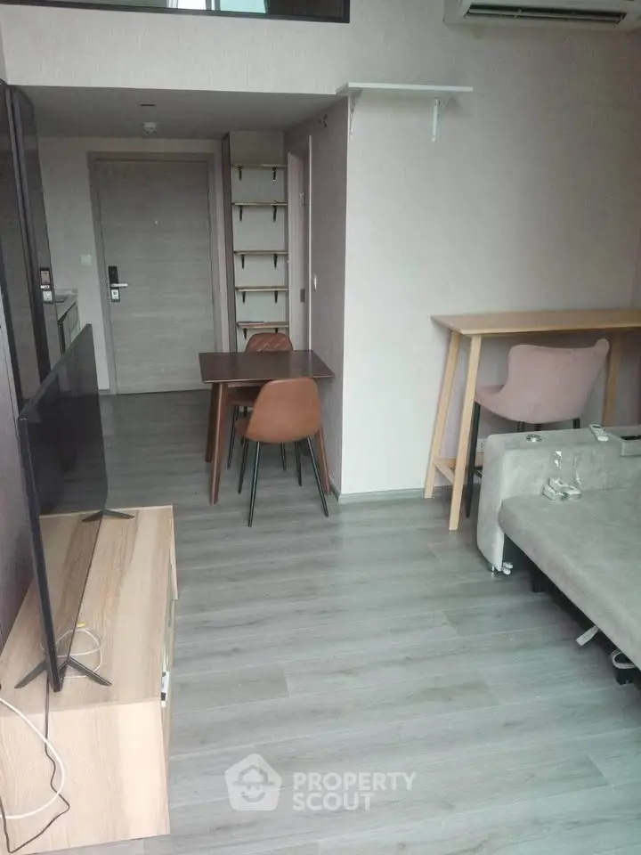 Modern living room with sleek furniture and open layout, featuring a TV and dining area.