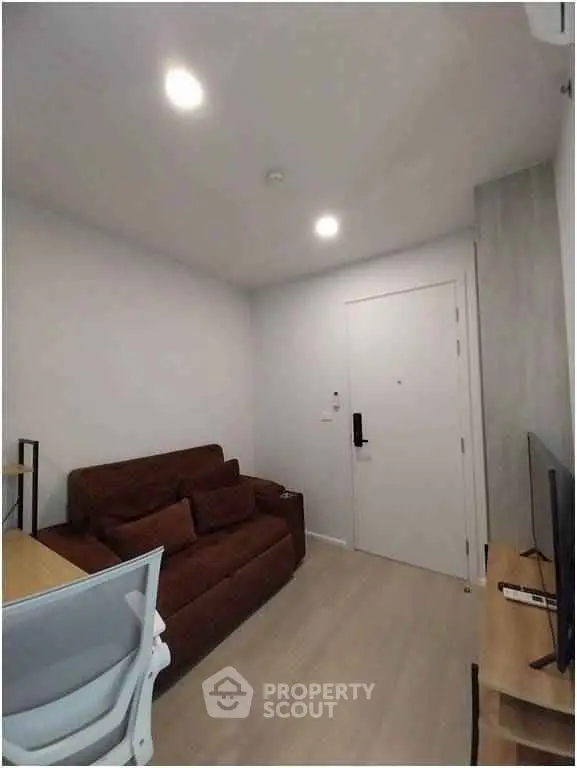 Cozy living room with brown sofa, modern decor, and flat-screen TV in a compact apartment.