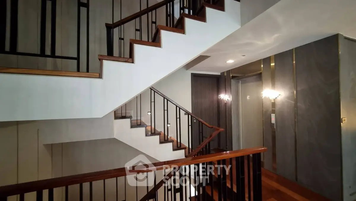Elegant modern staircase with sleek wooden railings and stylish lighting in a luxurious building interior.