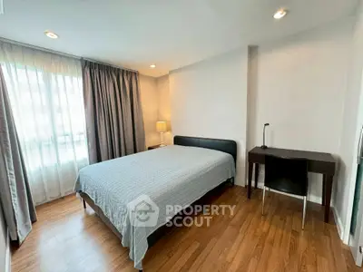 Spacious bedroom with modern decor and natural light in a stylish apartment.