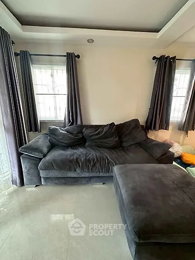 Spacious living room with plush dark sofa and natural light from large windows.