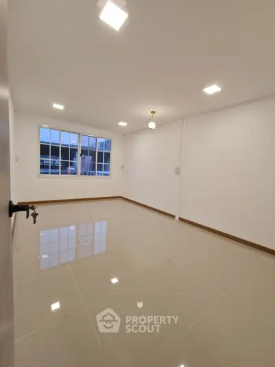 Spacious empty room with large windows and glossy tiled flooring, ideal for customization.