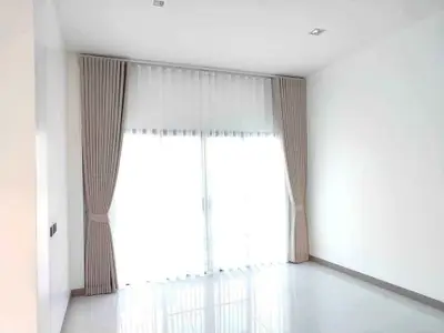 Spacious empty room with large window and elegant curtains, perfect for customization.