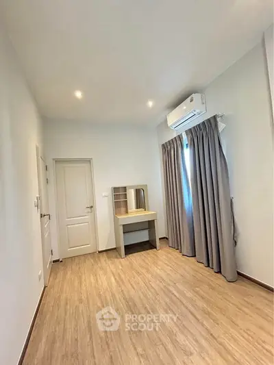 Spacious bedroom with wooden flooring and natural light