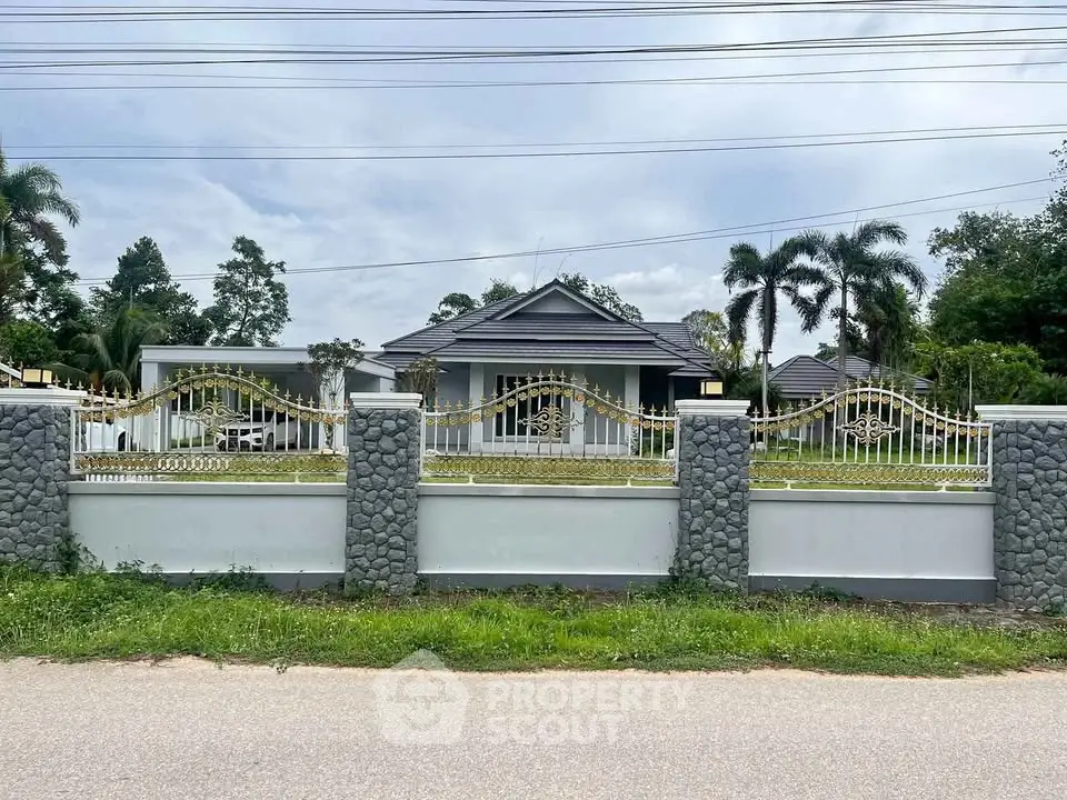 Charming suburban home with elegant wrought iron fence and lush greenery, perfect for family living.