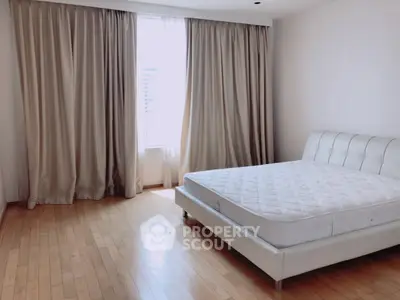 Spacious bedroom with large window and elegant curtains