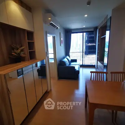 Modern living room with wooden flooring, stylish furniture, and large windows offering city views.