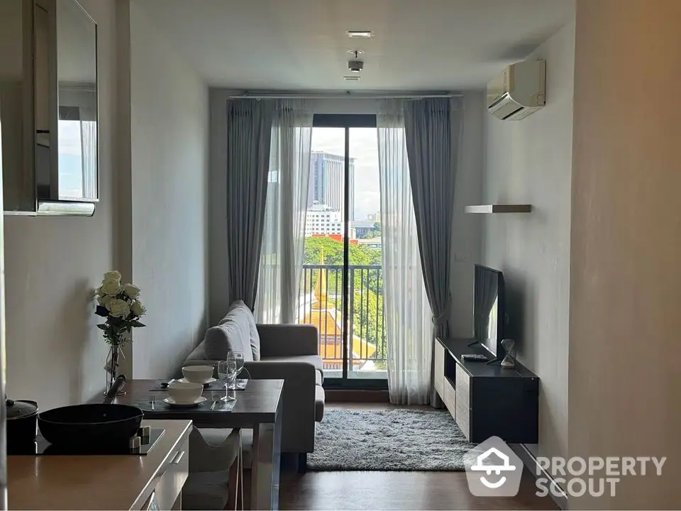 Modern living room with balcony view, sleek furniture, and natural light in urban apartment.