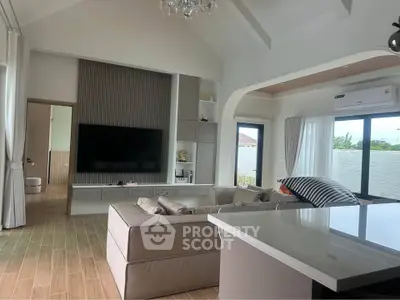 Spacious modern living room with high ceiling and large TV, featuring elegant decor and natural light.