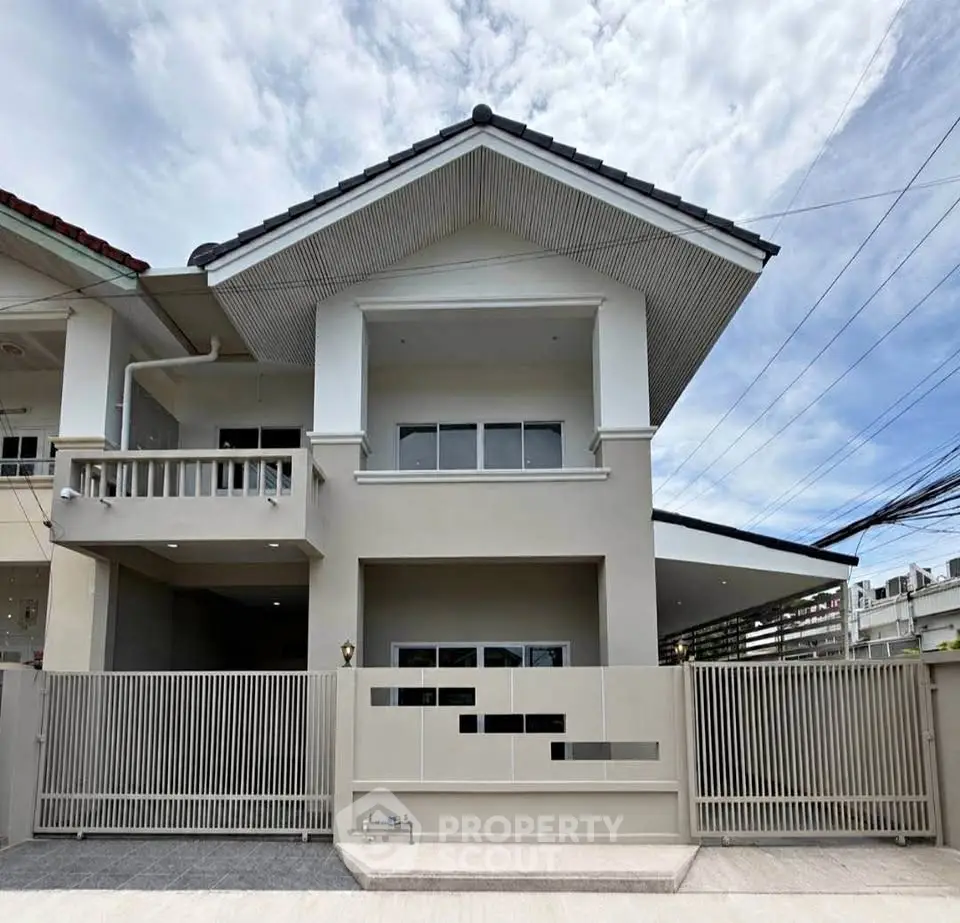 Modern two-story house with sleek design and spacious balcony in a suburban neighborhood.