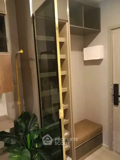 Compact modern storage area with built-in shelves and seating in a stylish apartment.