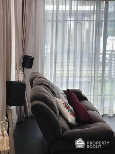 Elegant living room with plush sofa and sheer curtains offering natural light