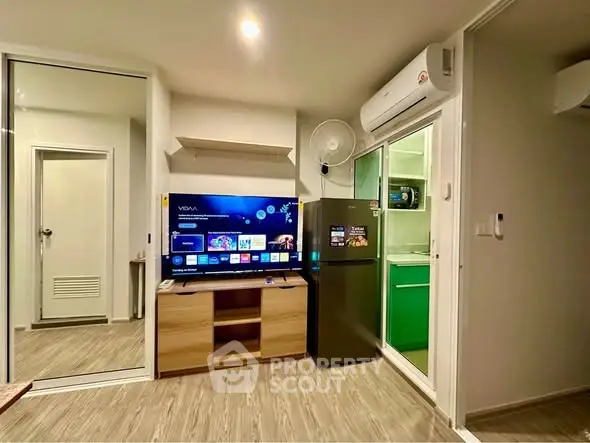 Modern living room with TV, fridge, and air conditioning in a cozy apartment.