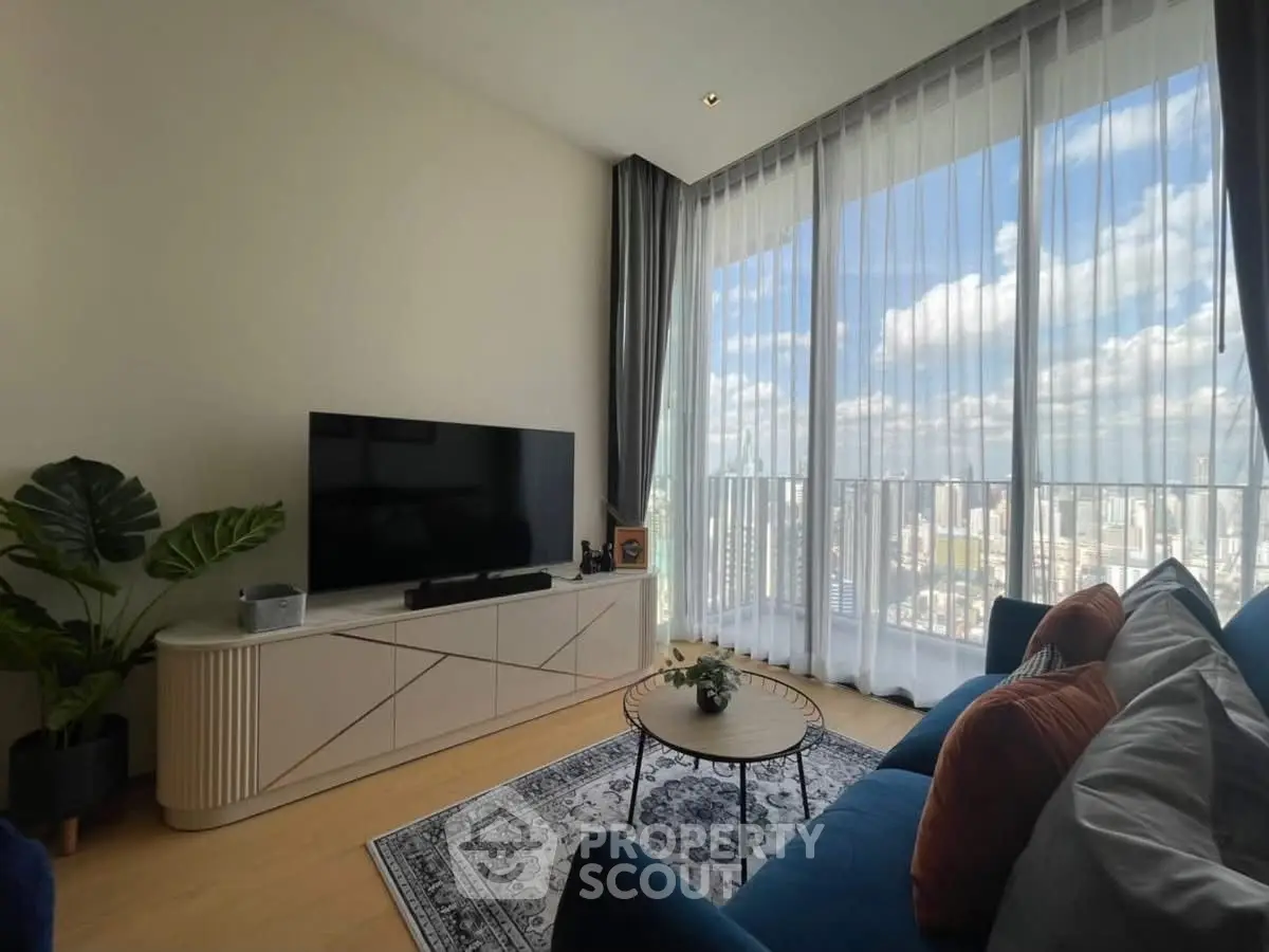 Modern living room with large windows offering stunning city views, featuring stylish furniture and decor.