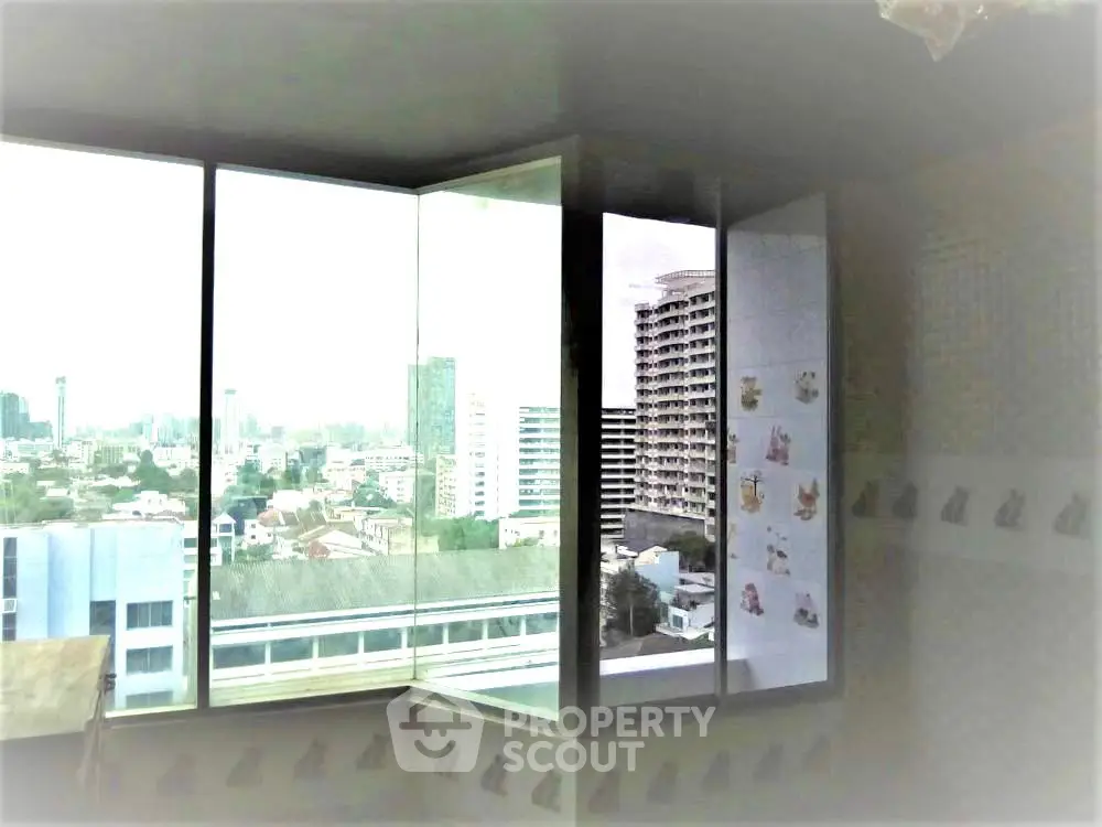 Spacious corner unit with panoramic city view from large windows in high-rise building.