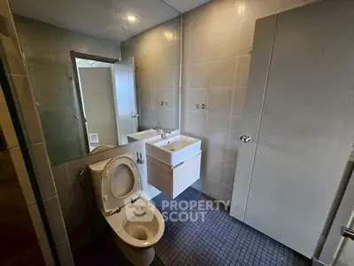 Modern bathroom with sleek fixtures and tiled walls, featuring a dual sink vanity and toilet.