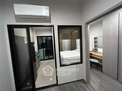 Modern apartment interior with bedroom and kitchen view, featuring sleek design and air conditioning.
