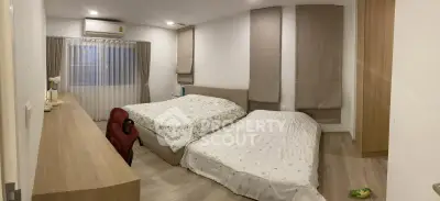 Spacious bedroom with two beds, modern decor, and ample natural light.