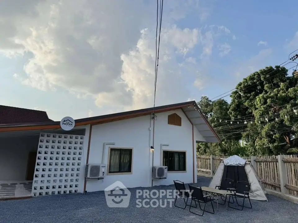 Charming single-story home with outdoor seating and tent, perfect for nature lovers.