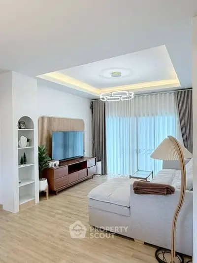 Modern living room with stylish decor, large TV, and natural light from floor-to-ceiling windows.