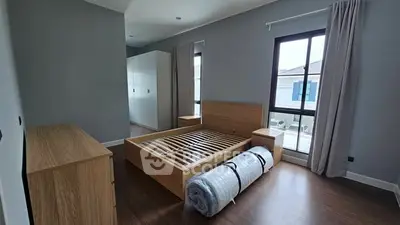 Spacious bedroom with wooden flooring and large window offering natural light.