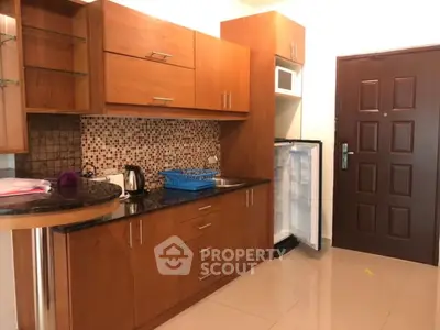 Modern kitchen with wooden cabinets and mosaic backsplash in cozy apartment.