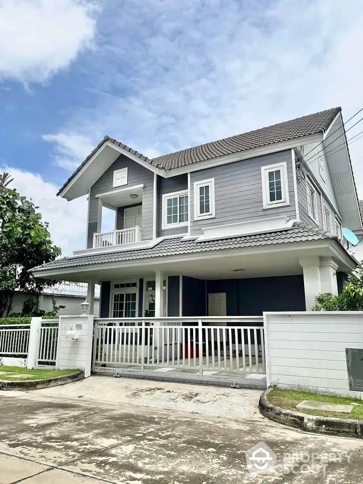 Charming two-story gray house with white accents and spacious driveway in a serene neighborhood.