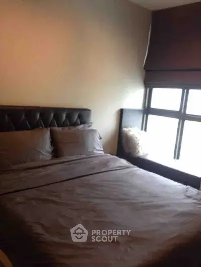 Cozy bedroom with large window and stylish bed in modern apartment.