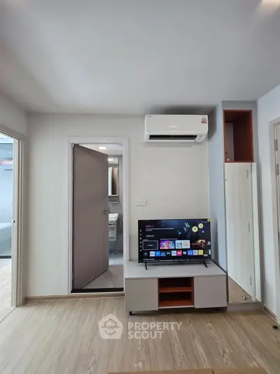 Modern living room with sleek TV setup and air conditioning in a stylish apartment.