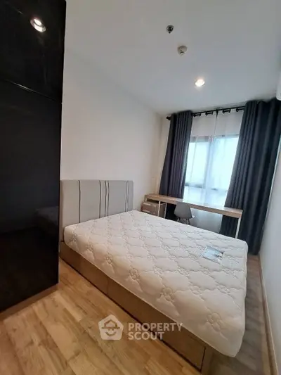 Modern bedroom with large window and wooden flooring, featuring a cozy bed and study desk.