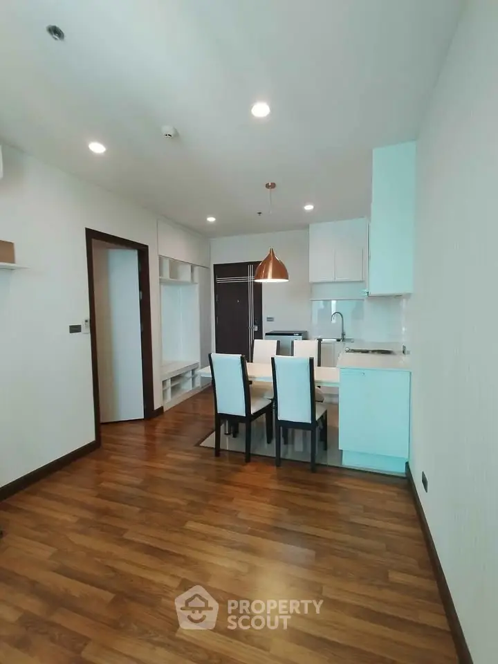 Modern open-plan kitchen and dining area with wooden flooring and stylish lighting.