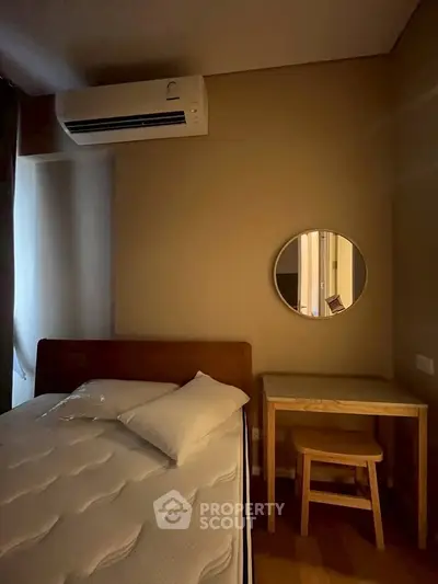 Cozy bedroom with air conditioning and minimalist decor, featuring a comfortable bed and a small desk with a mirror.