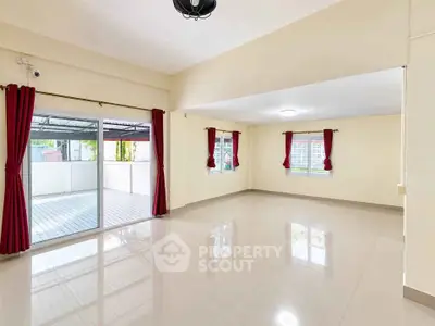 Spacious empty living room with large windows and sliding doors to balcony, featuring glossy tiled floors.