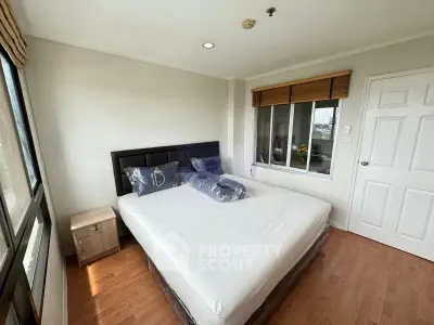 Cozy bedroom with large windows and wooden flooring in modern apartment