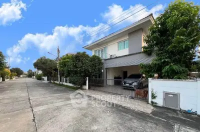 Charming suburban house with driveway and lush greenery under a bright blue sky.