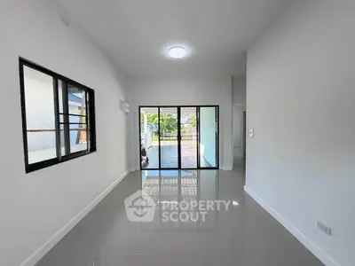 Spacious modern living room with glossy floors and large windows opening to a garden view.