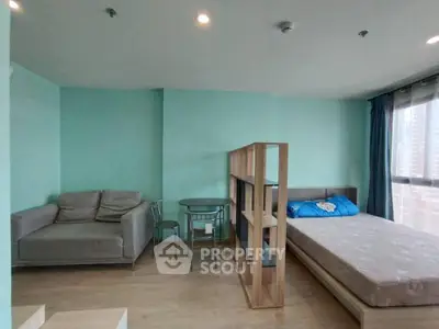 Modern studio apartment with cozy living area and bed, featuring a partition for privacy.