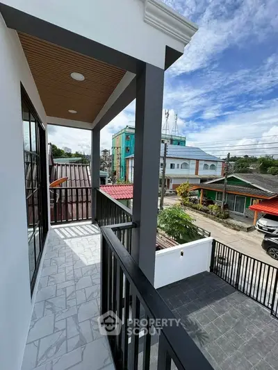 Spacious balcony with modern railing offering a vibrant neighborhood view, perfect for relaxation.