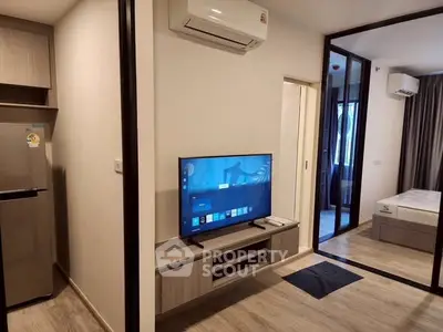 Modern apartment interior with sleek design, featuring a living area with TV and adjacent bedroom.