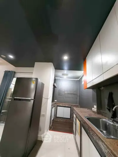Modern kitchen with sleek cabinetry and stainless steel fridge in a stylish apartment.