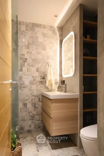Modern bathroom with marble tiles and illuminated mirror